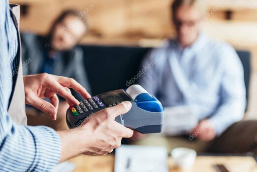 Commerciante al banco che emette uno scontrino da un registratore di cassa